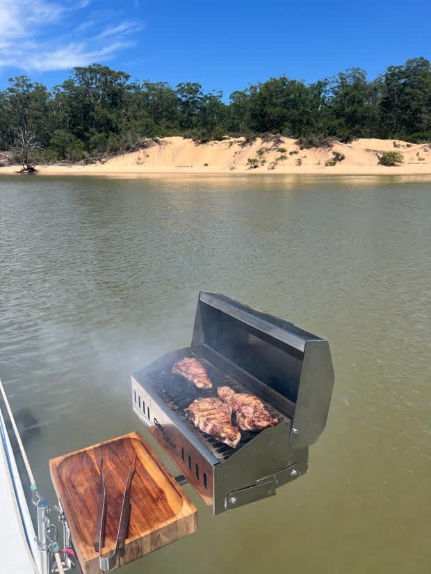 Churrasco na churrasqueira do veleiro, com a margem do rio ao fundo
